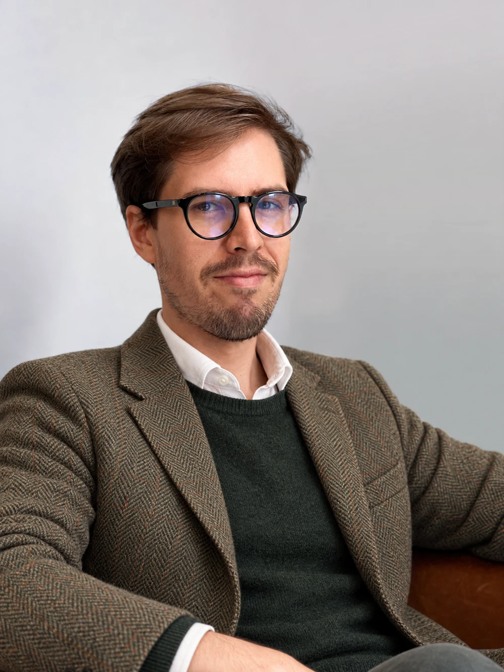Anthony Miller wearing a tweed jacket and forest-green knitwear